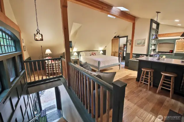 You are at the top of the stairs. The Douglas Fir floors and meticulous craftsmanship continues throughout the guest suite. The bathroom is through the door with the barn door. Note the stunning custom window along the left edge of this photo.