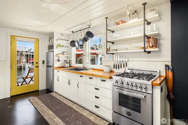 Kitchen with large deep sink and stainless Bertazzoni range. New fridge microwave and open shelving with plenty of cabinet space. Space to grill off the back deck.