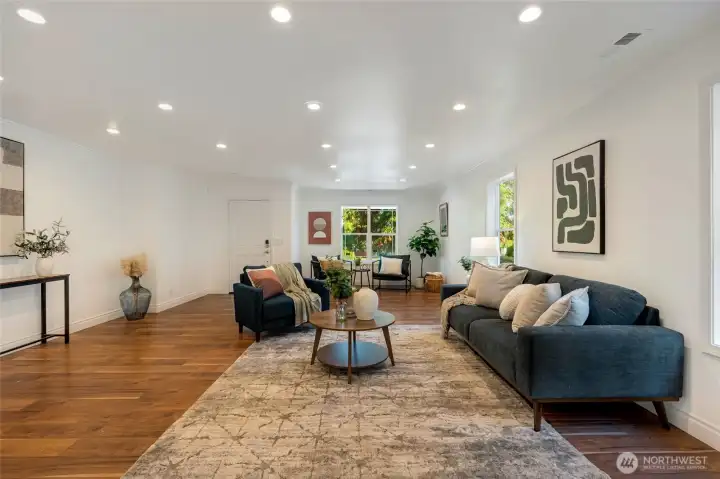 The living room is equally impressive—an expansive, light-filled space with gleaming hardwood floors and a cozy double-sided fireplace connecting seamlessly to the dining and kitchen areas.