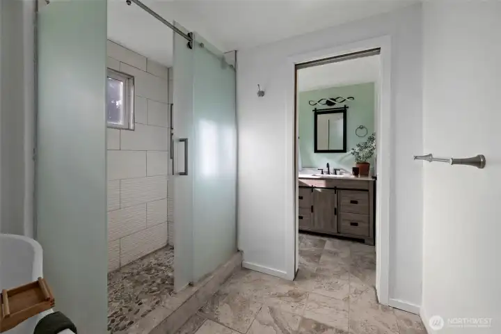 Pocket door separates shower and soaking bathtub room from sink and toilet.