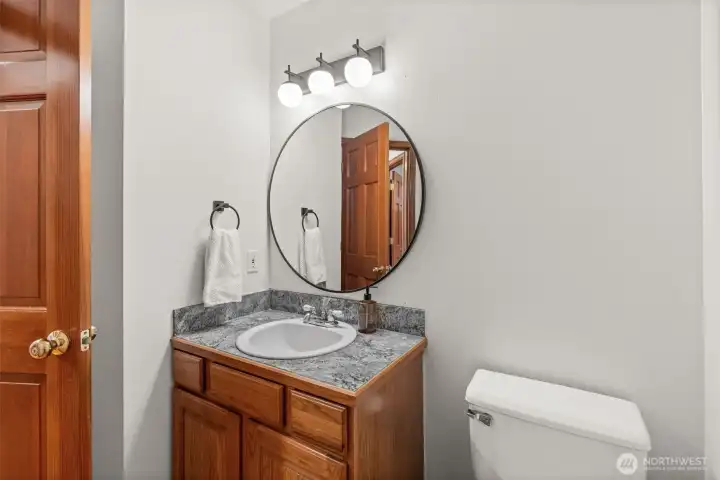 Main floor half bathroom with updated fixtures, mirror, and hardware.