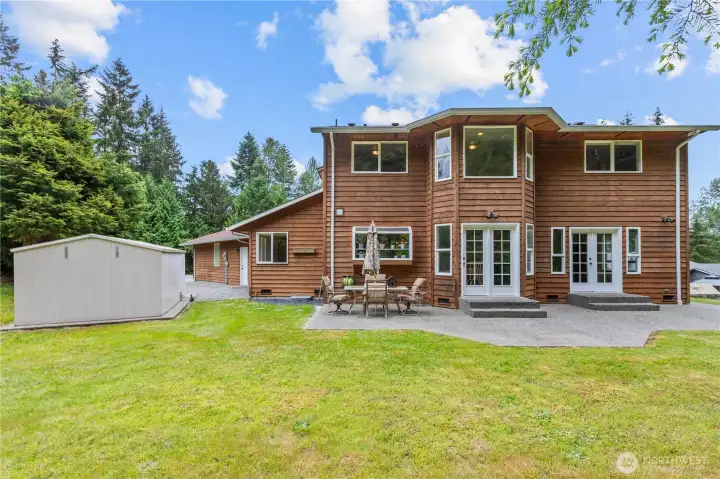 A view of the back of the home, patio, yard and shed