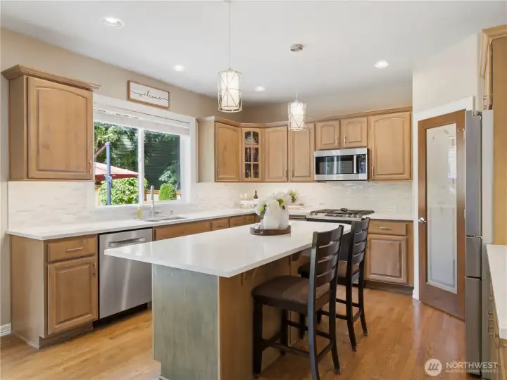 Stunning kitchen featuring new quartz countertops, stainless steel appliances, abundant cabinetry, walk-in pantry, and an oversized center island with seating.