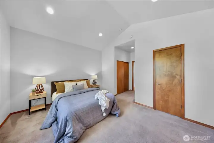 Second-floor primary suite with vaulted ceilings and two closets including walk-in