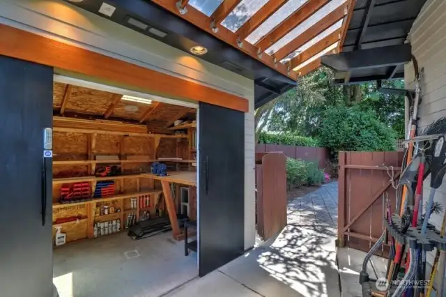 A woodworkers dream with a custom bench and vice.  Note that the area between the shed and garage is covered, which provides welcome cover from rainy days!