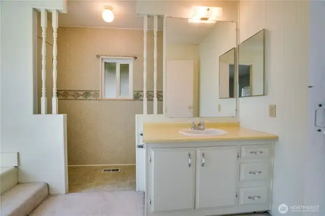 The primary bathroom needs a bit of a refresh, but it is ready for your personal touch. There is a linen closet and this generous vanity with storage too.