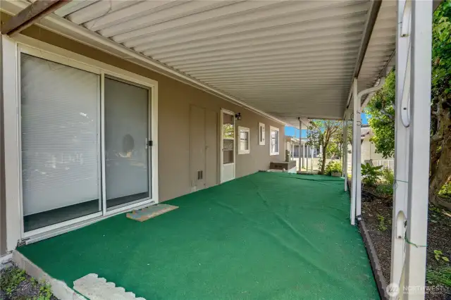 The dining room sliding glass door also steps out to this covered area. Let's head out to the back of the home and check out the carport and extra storage spaces.