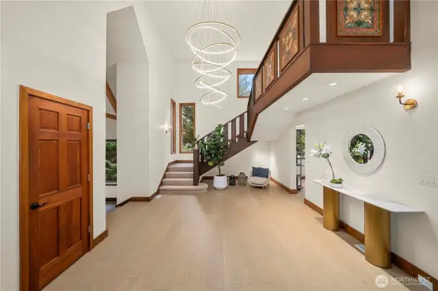 Grand entryway with soaring ceilings, beautiful lighting, and rich engineering hardwood floors sets the tone for refined living