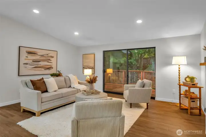 The large slider opens to a deck and back yard surrounded by trees.