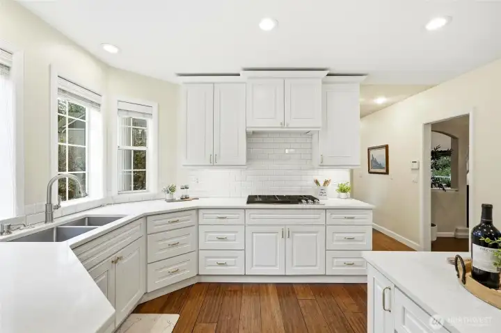 Bright eat-in kitchen with expansive windows overlooking the private wooded setting and Lake Wilderness views, offering seamless indoor-outdoor connection.