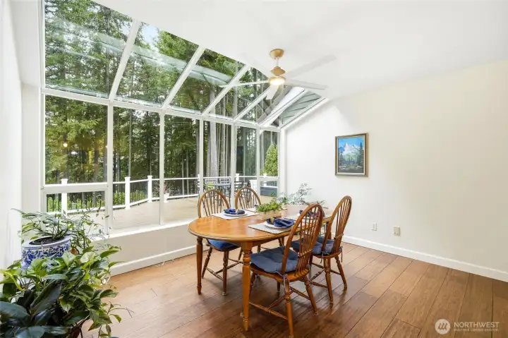 Light-filled casual dining space with expansive windows framing lake and wooded views—ideal for morning coffee or sunset dinners.