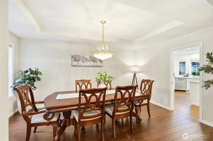 Elegant formal dining room with chandelier and warm wood flooring, perfect for hosting in this Maple Valley luxury home.