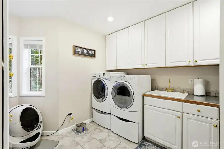 Functional laundry room with cabinetry and full-size washer/dryer, offering convenience in this 4-bedroom Maple Valley home.