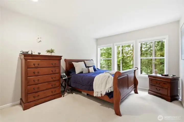 Spacious secondary bedroom with large windows and peaceful wooded views, perfect for guests or family in this 4-bedroom Maple Valley home.