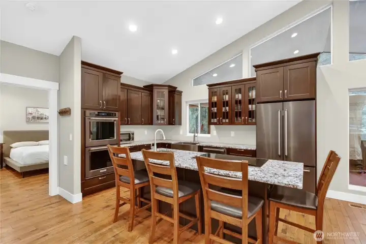 Open kitchen with stainless steel appliances, dual ovens, granite countertops and a 4-seater island.
