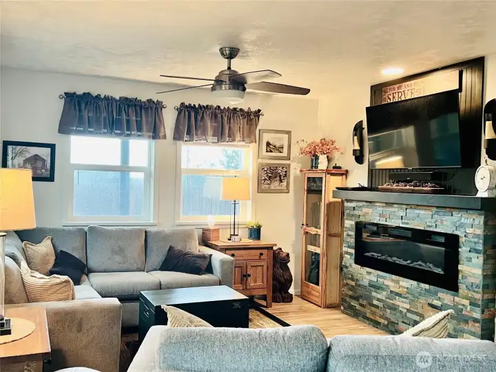 In the living room with furniture, beautiful electric fireplace with stone surround makes for a cozy, warm environment.