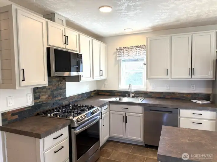 The kitchen is well planned and stylish with its white cabinets and warm colored countertops.