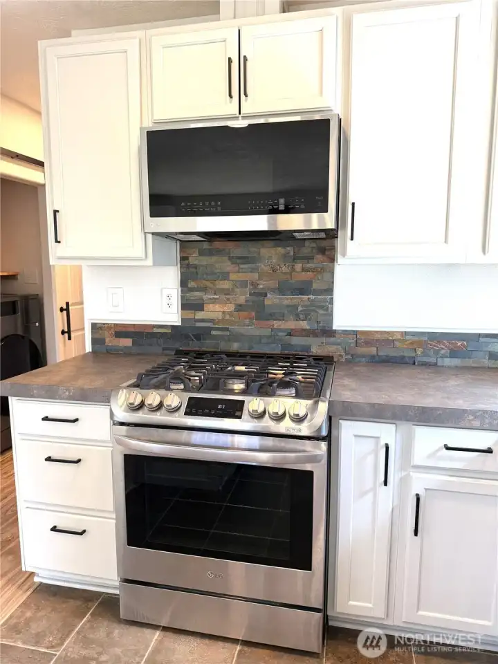 Propane range is a wonderful feature with a microwave above. The stone from the fireplace is carrierd over to the kitchen as a design element.