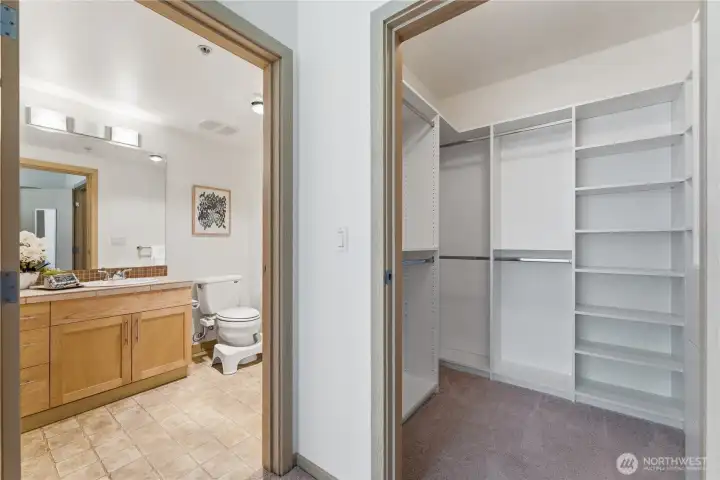 Hallway view showing the primary bathroom beside the walk-in closet