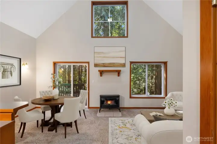 Vaulted ceilings soar overhead, creating a sense of openness, while oversized windows frame views of the forest and glimpses of the lake beyond.