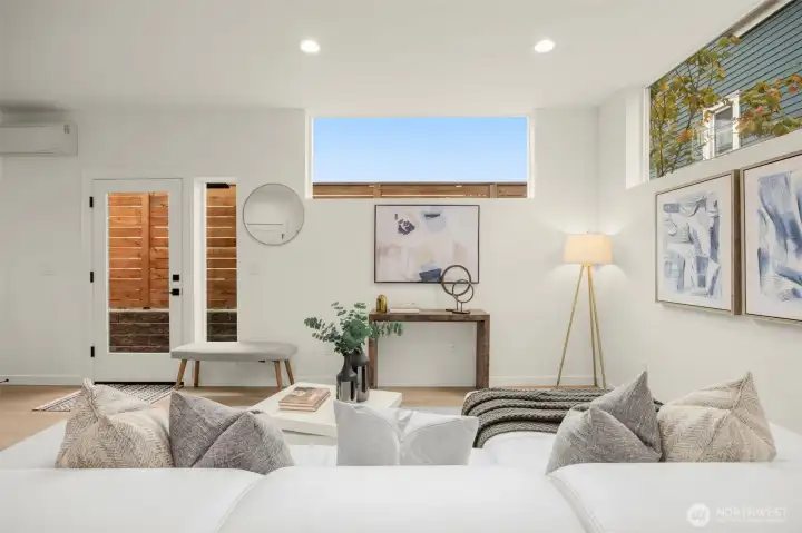 Soft daylight pours through oversized windows, filling the room with warmth and a sense of calm connection to the outdoors.