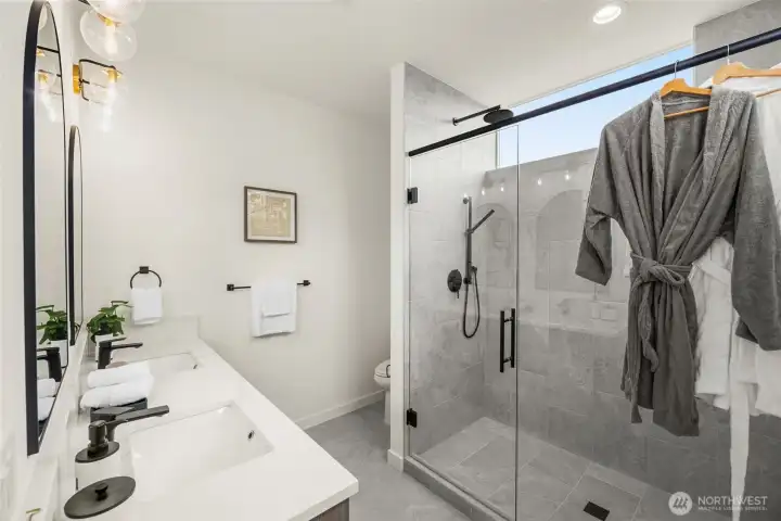 A glass shower glows with crisp tile and clean lines. Everyday rituals elevated by thoughtful design.