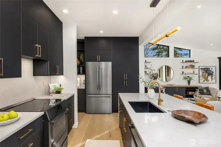 The kitchen sparkles with solid surface quartz countertops, an induction stove, speed oven and French door refrigerator.