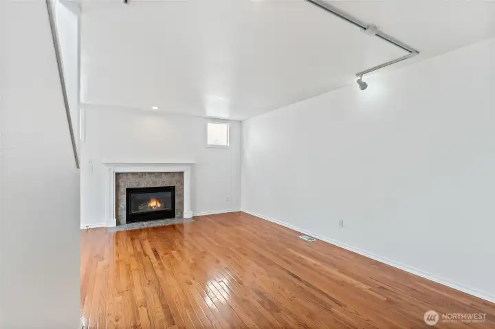 Living room with hardwood floors. Gas fireplace with mantle. Track lighting.
