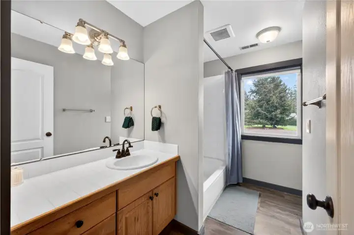 Updated main bathroom offers quartz countertops, updated sink and fixtures, and a clean modern feel with easy access for guests and secondary bedrooms.