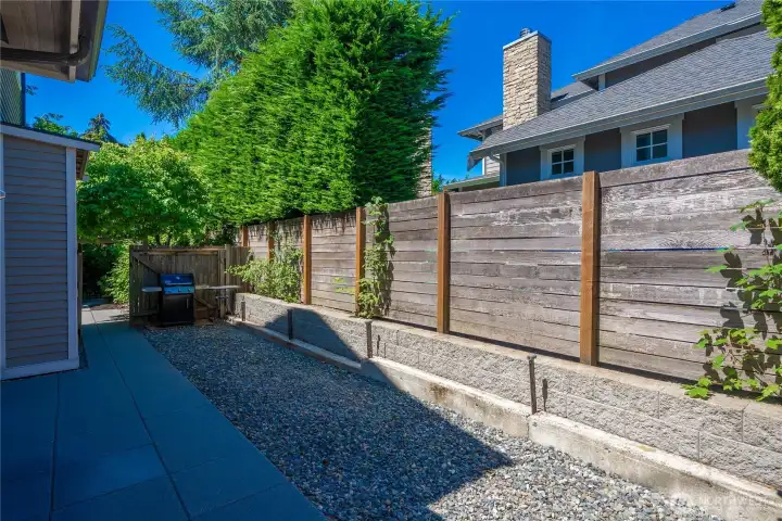 Tall fencing provides privacy and an expanded backyard area with patio and gravel space. Plenty of room for storage.