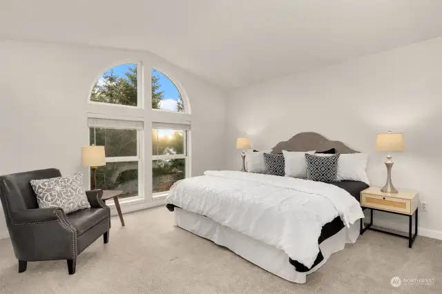 Primary bedroom with vaulted ceilings and light loving windows.