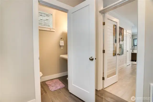 Here is the half bath that serves the downstairs living area- so conveniently located for those enjoying the hot tub out back! Let's head upstairs! (Stairs are to the left once you enter back into the kitchen.)