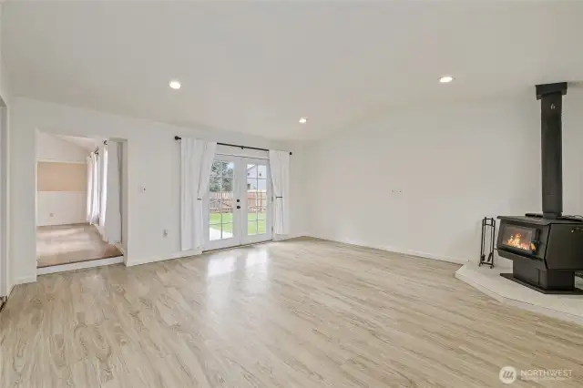 Large living room with wood stove and french doors to patio and backyard.