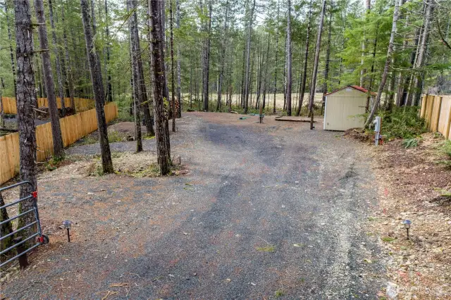 This cleared and level lot offers a gravel driveway leading to a spacious area between mature trees, providing privacy and a peaceful atmosphere. Ready for RV use or future development. A storage shed is located toward the back for added convenience, and the fencing enhances privacy.