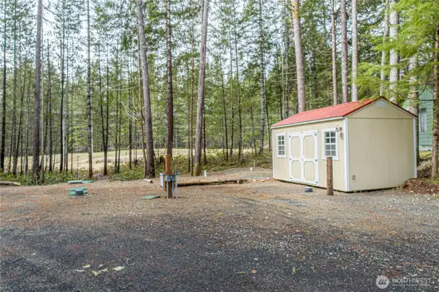 This photo highlights the utility setup and storage shed located toward the back of the lot. The utility connections, including water, power, and septic, are easily accessible and ready for immediate use — perfect for RVs or future construction.