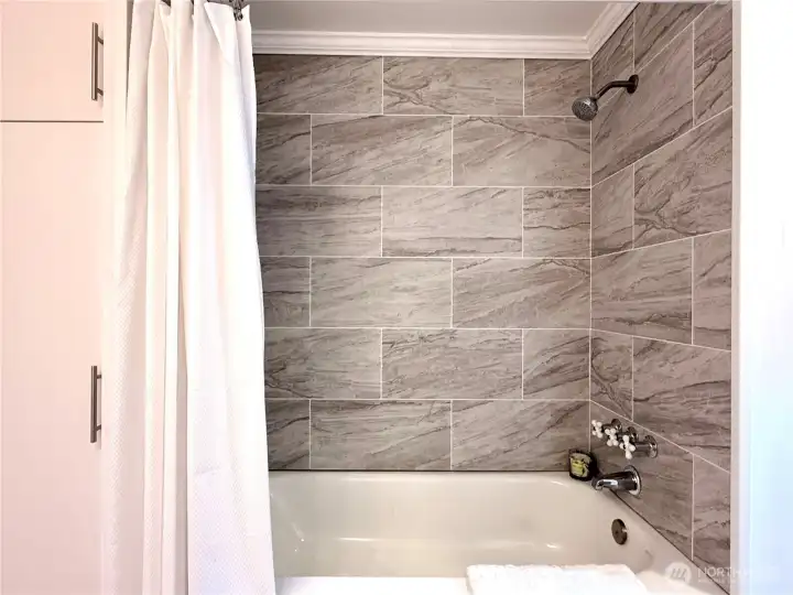Storage to left of shower tub with beautiful new tile