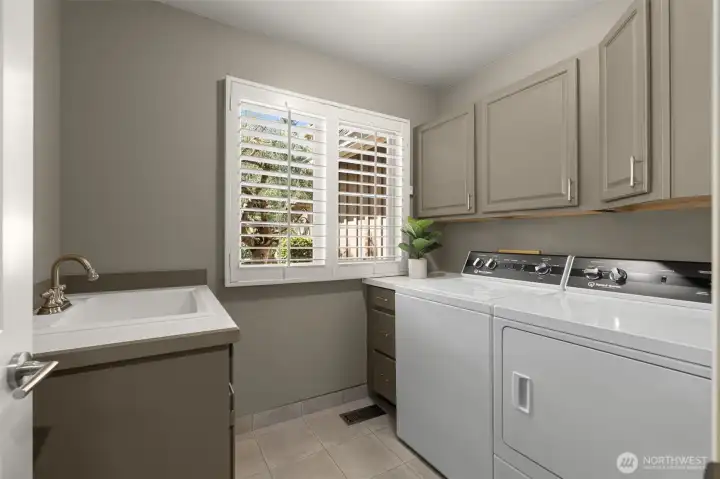 Main floor laundry room with sink and storage cabinets