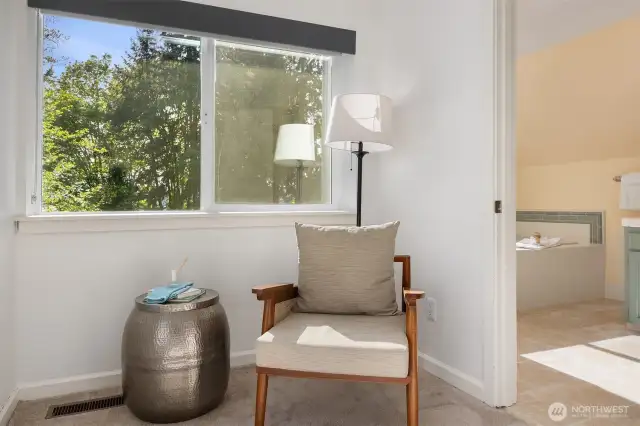 Cozy seating area just off the spacious bathroom, featuring a west-facing window with blackout blind and remote-controlled shade.