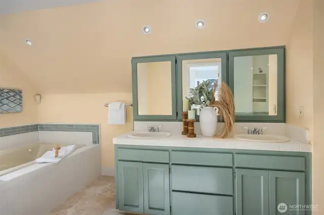 Dual vanities in a calming muted green palette, enhanced by abundant natural light at the mirrors—an inviting space to start the day.