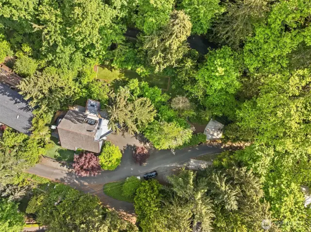 From above, see how this retreat is perfectly situated: a large circular driveway, two flat play areas, a babbling creek, and extra parking space that doubles as a sport court. Surrounded by trees yet filled with natural light—as the aerial view beautifully shows.
