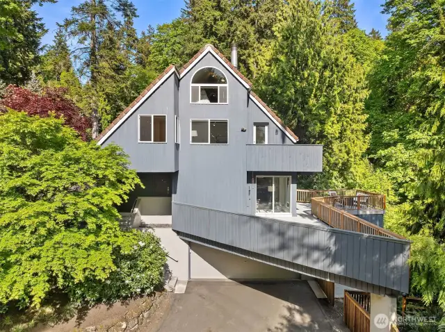 West-facing front shaded by mature trees offering privacy and curb appeal. Two spacious decks provide seamless indoor-outdoor flow—ideal for entertaining or unwinding. Ample parking with a large circular driveway and additional flat space nearby.