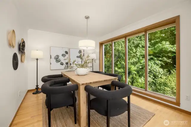 The formal dining area boasts floor-to-ceiling windows that frame the serene wooded setting, bringing the beauty of nature indoors.