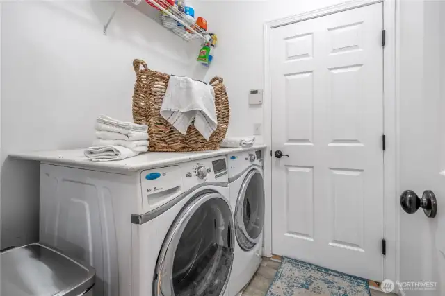 Large pass-through laundry room with storage above and access to the garage beyond.