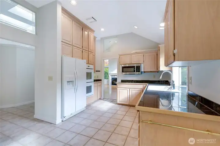 The spacious kitchen features an eating area, a French door pantry, double ovens, soaring ceilings, and abundant natural light from the new windows.