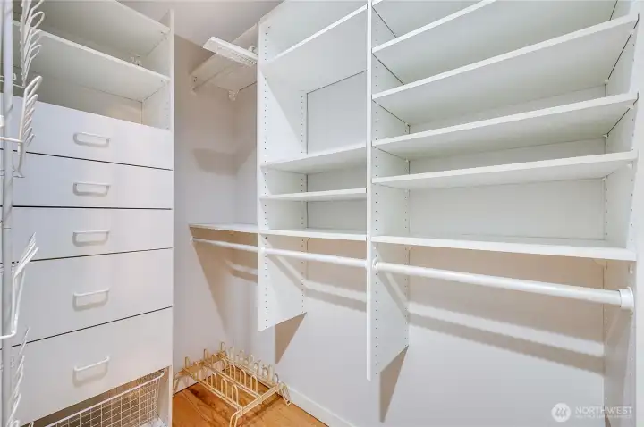 The primary bedroom offers a generous walk-in closet with built-in shelving and ample storage, complemented by a second closet across the hall for additional wardrobe space.