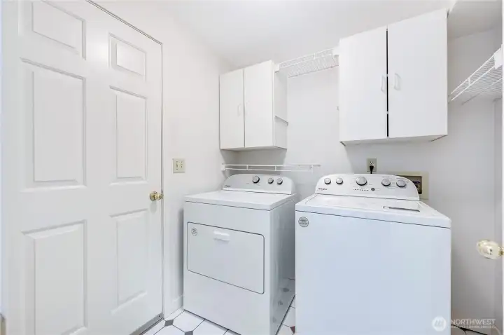 The utility room is off of the garage and has storage, hanging racks, and a cubby hole for more storage to the right.