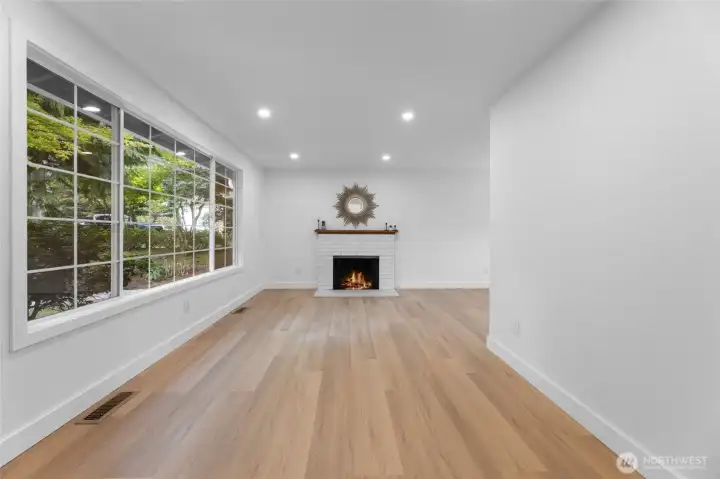 Open flowing living room with wood-burning fireplace. New flooring, baseboard trim and fresh paint throughout house.