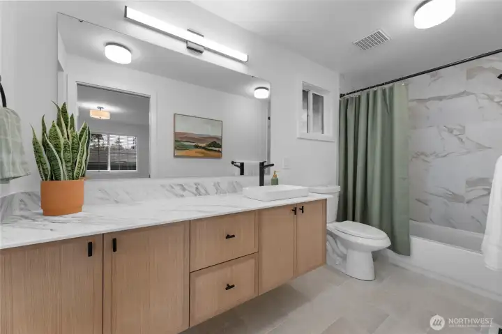 Refreshed primary bathroom with new floor tile, vanity, counter top as well as new shower fixture and toilet.