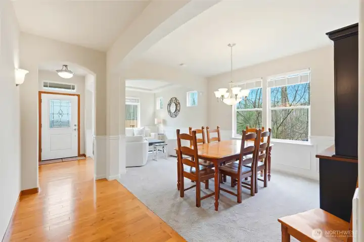 Formal dining room with chandelier, wainscoting, and large windows overlooking trees Formal dining room with chandelier, wainscoting, and large windows overlooking trees
