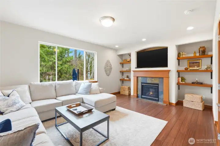 The kitchen opens to a large family room with a gas fireplace and picture windows framing the wooded backdrop. The kitchen opens to a large family room with a gas fireplace and picture windows framing the wooded backdrop.